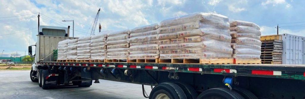 A truck bed filled with pallets of bagged cement