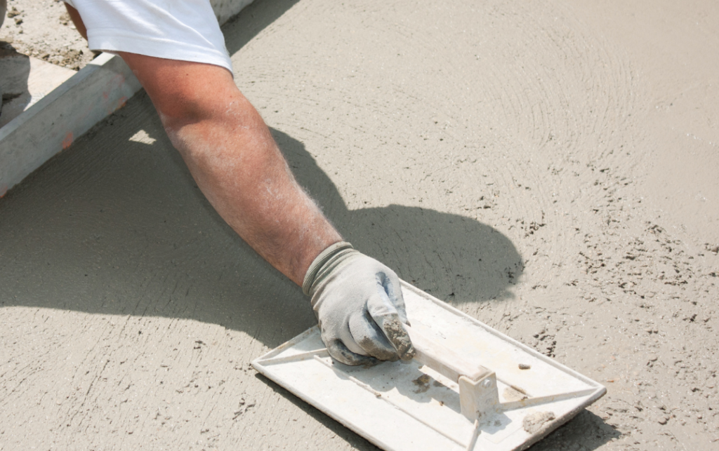 Construction worker spreading masonry cement to create concrete