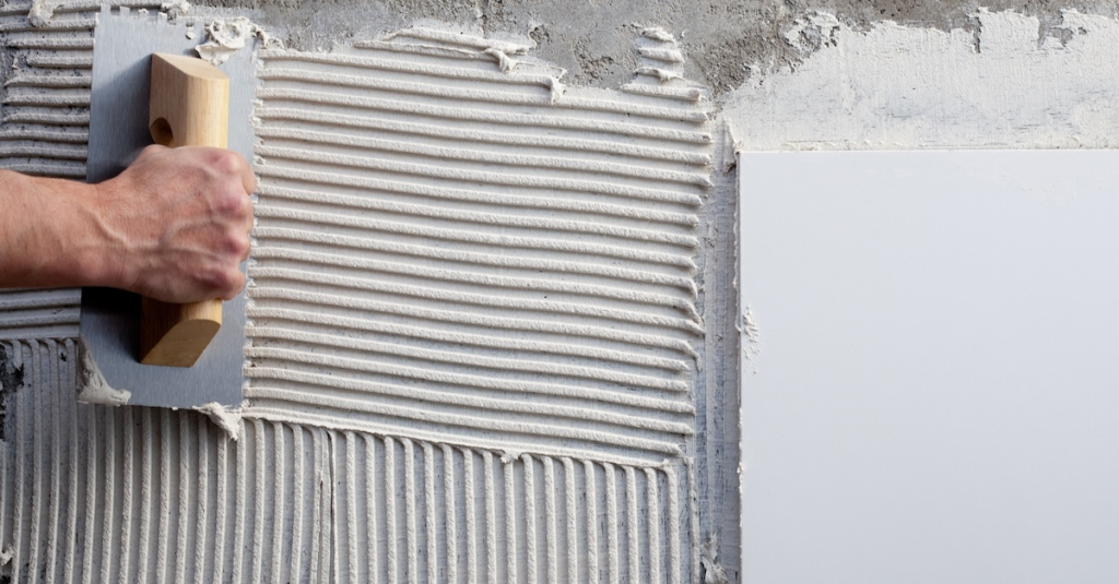 Worker spreading masonry white cement during a construction job